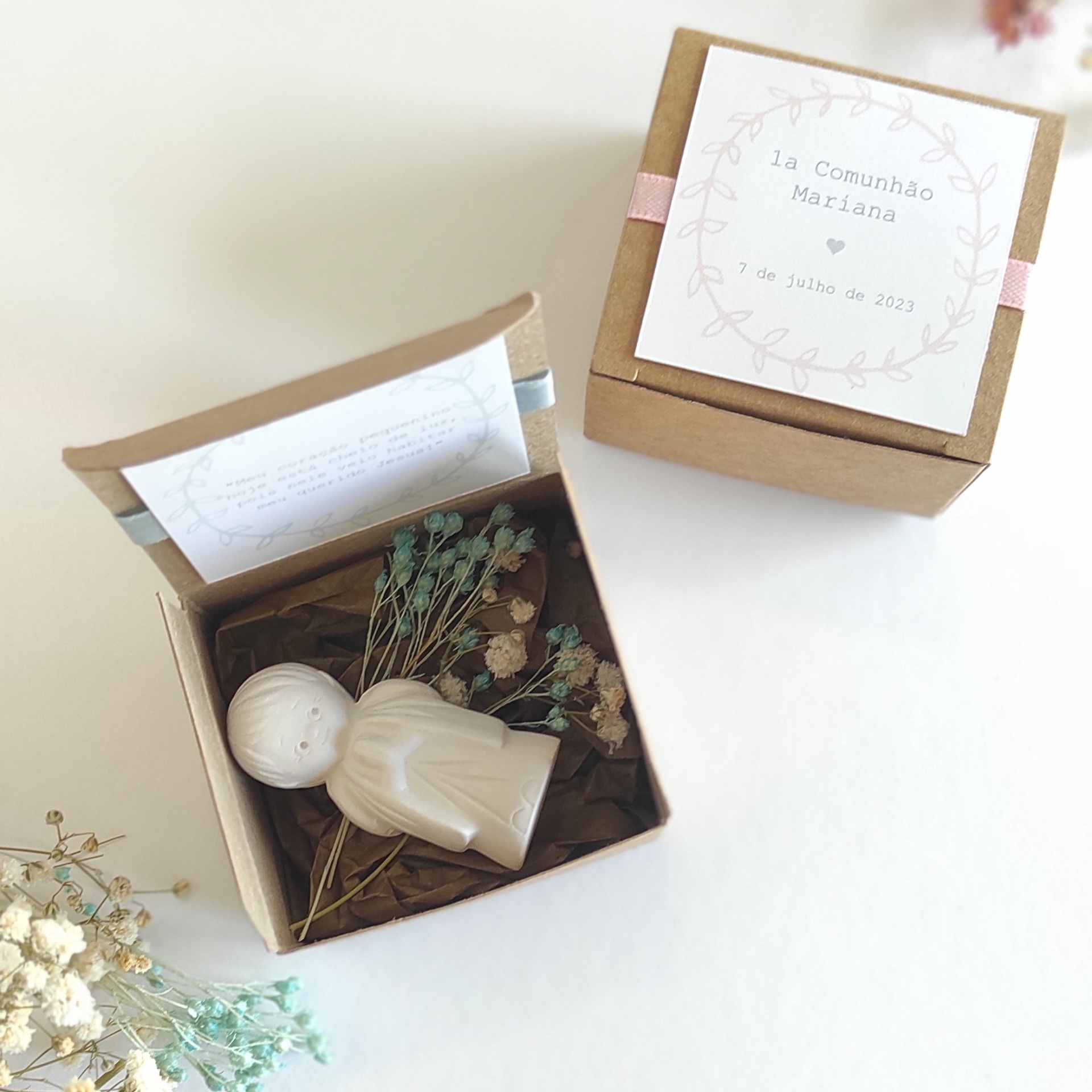 Caixa kraft com figura cerâmica branca e flores secas, com etiquetas de primeira comunhão