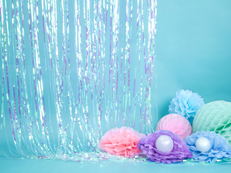 Decoração festiva com cortina prateada e flores de papel coloridas num fundo azul