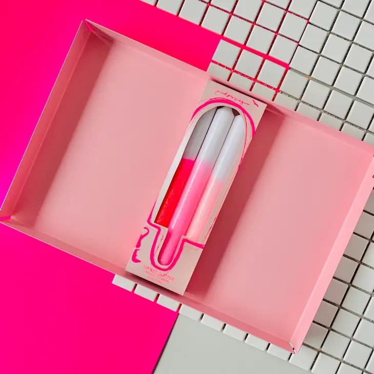 Caixa rosa aberta com pulseira de silicone branca e rosa dentro, sobre fundo quadriculado branco e superfície rosa