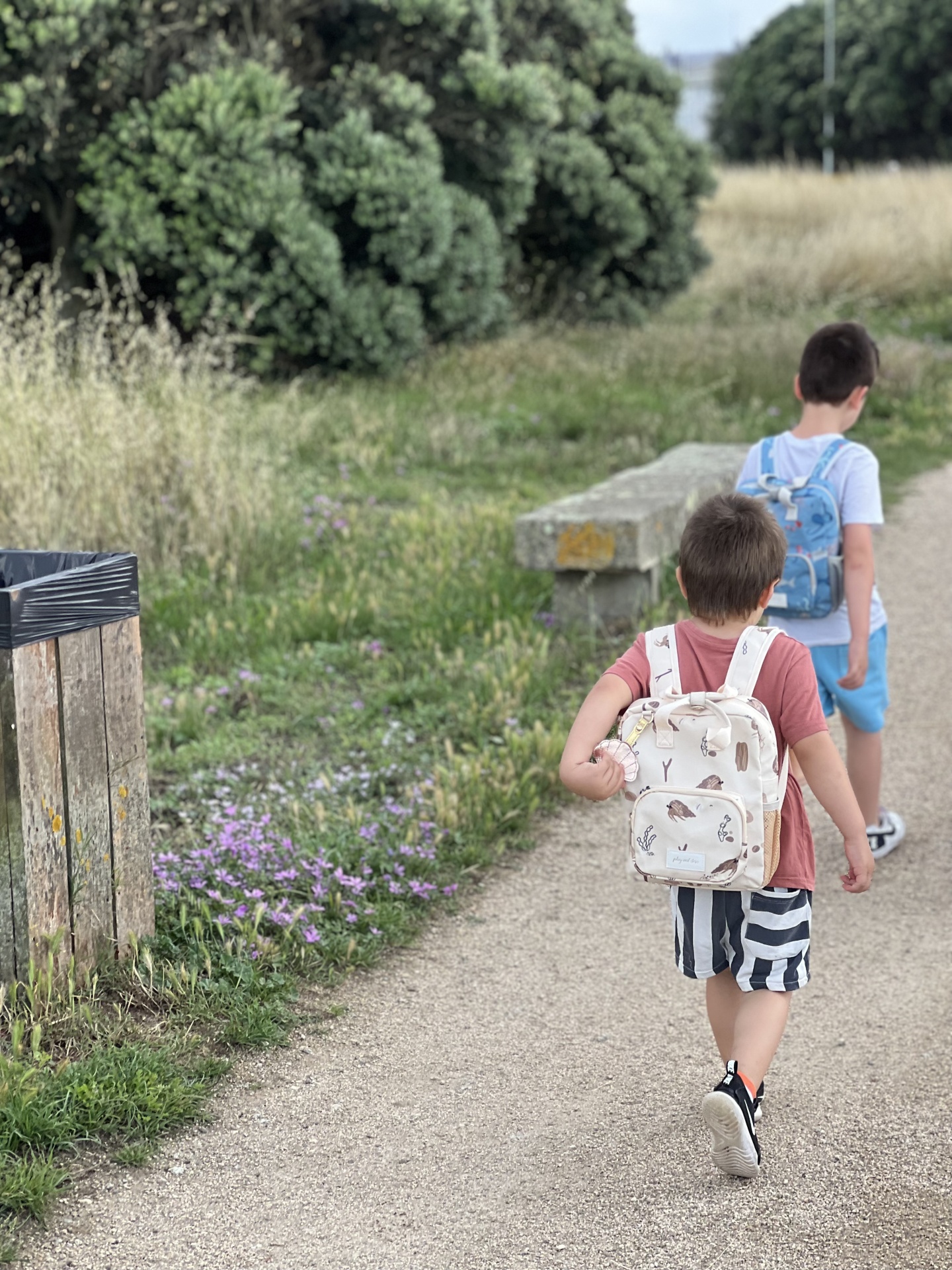 Duas crianças com mochilas a caminhar num caminho ao ar livre