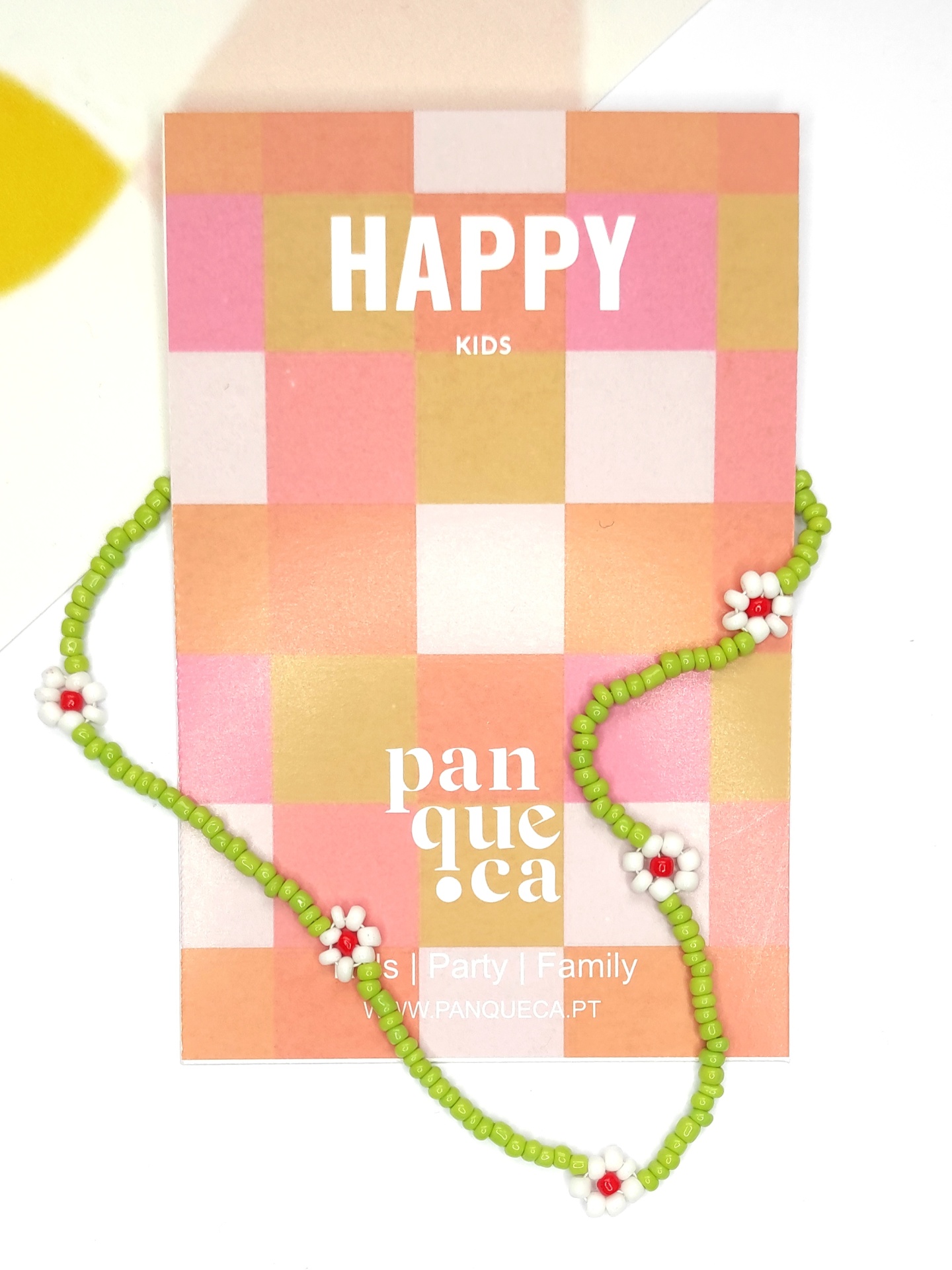 Colar infantil com contas verdes e flores brancas sobre cartão colorido com texto