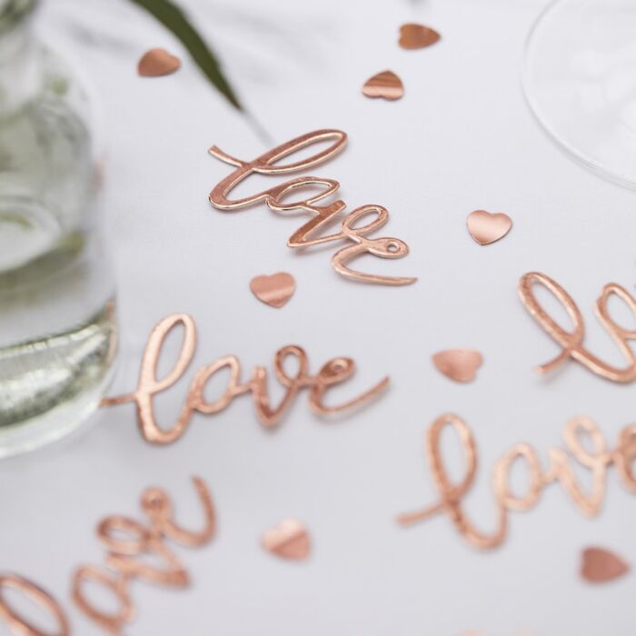 Confetes em forma de 'love' e corações em cobre sobre fundo branco