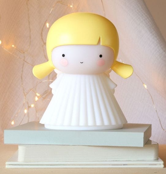 Figura decorativa com cabelo amarelo e vestido branco sobre livros