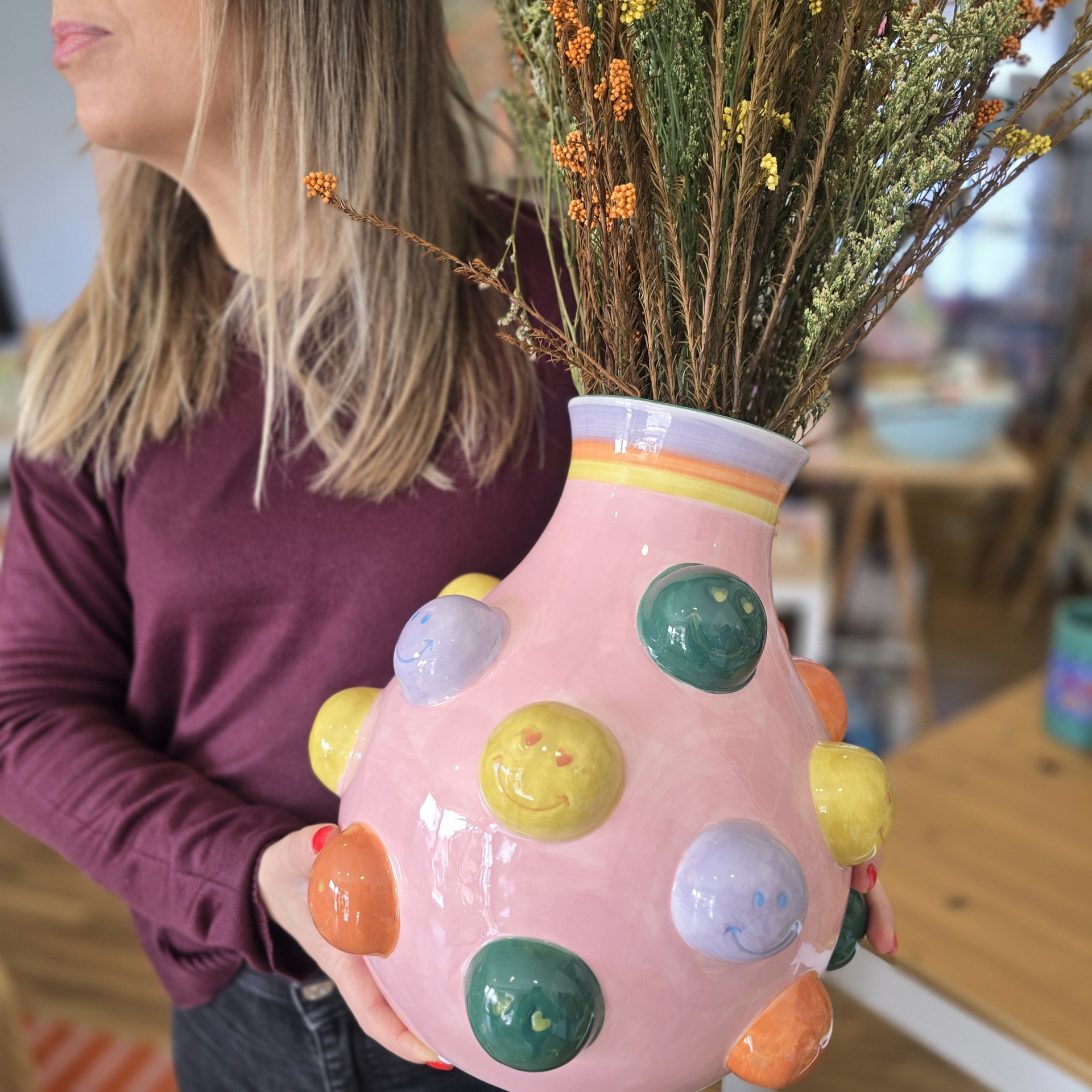 Vaso de cerâmica rosa com bolbos coloridos e flores secas