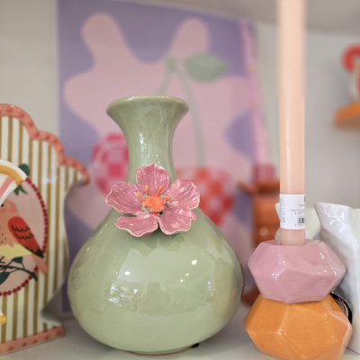 Vaso decorativo verde claro com flor rosa e castiçal cor de rosa
