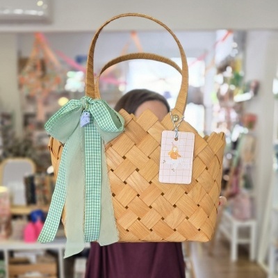 Cesto de palha bege com laço verde e etiqueta panuuca