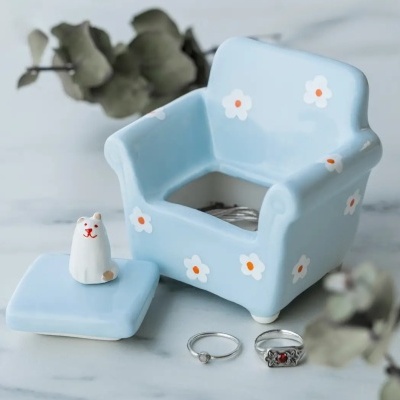Caixa cerâmica azul clara em forma de poltrona com flores brancas e tampa com gato cerâmico branco