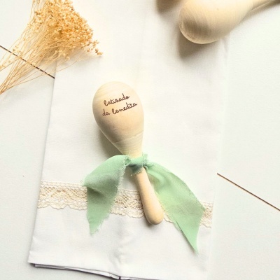 Colher musical de madeira com fita verde sobre pano branco com renda
