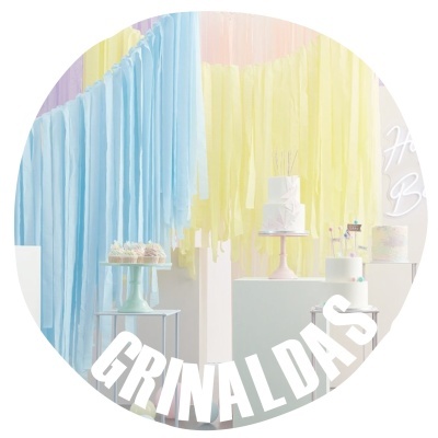 Decoração festiva com franjas de papel coloridas e bolos brancos em suportes