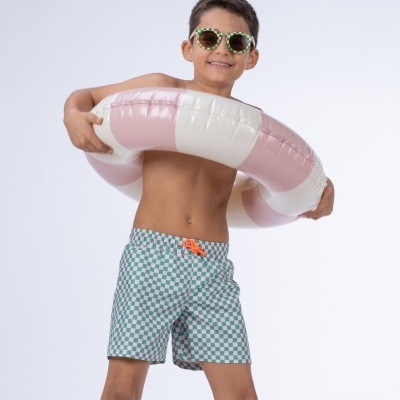 Menino com bóia insuflável branca e rosa e calções de banho quadriculados azul e branco