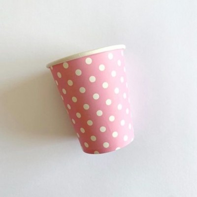 Copo de papel rosa com bolinhas brancas sobre fundo branco