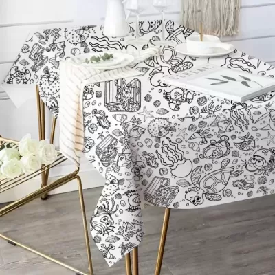 Toalha de mesa com desenhos humorísticos a preto de animais marinhos, numa mesa com pernas douradas.