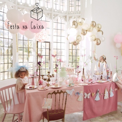 Festa infantil decorada com mesa rosa, balões e meninas vestidas de princesa