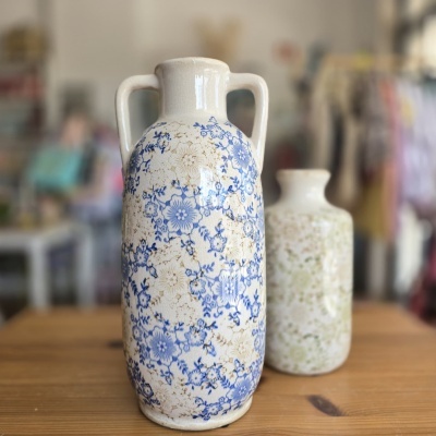 Dois vasos cerâmicos decorados com padrões florais sobre uma mesa de madeira.