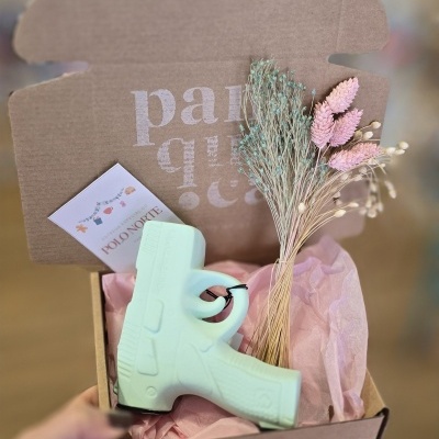 Caixa de cartão aberta com sabonete em forma de pistola e flores secas dentro