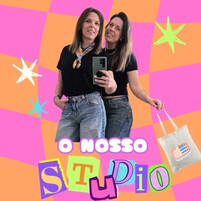Duas mulheres com t-shirts pretas e calças de ganga em fundo colorido rosa e laranja com estrelas e texto O NOSSO STUDIO.