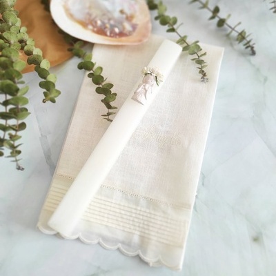 Guardanapo branco com vela decorada e ramos de eucalipto sobre superfície de mármore