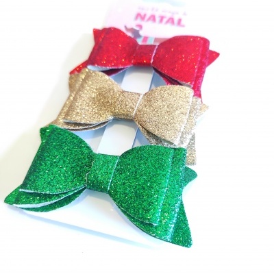 Três laços com glitter vermelhos, dourados e verdes para decoração de Natal num cartão branco