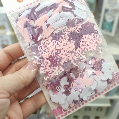 Pacote com confetes coloridos em formas diversas, embalados em plástico transparente.