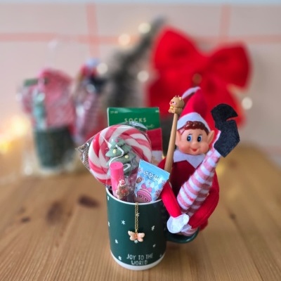 Caneca verde com presentes de Natal e boneco elfo