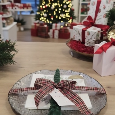 Prato decorativo com vela, guardanapo e fita xadrez em mesa de madeira com decoração natalícia ao fundo