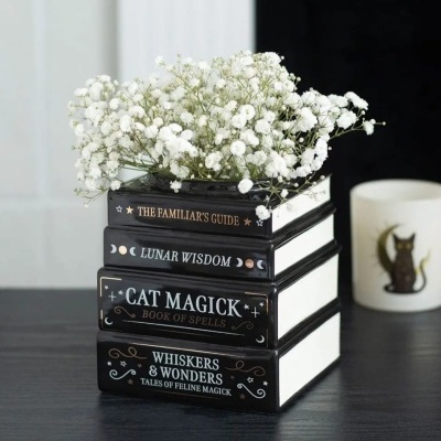 Vaso decorativo em forma de pilha de livros com flores brancas em cima