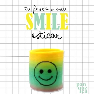 Suporte para vela colorido com sorriso e texto motivacional em fundo quadriculado.