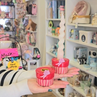 Bases de vela decorativas vermelhas e rosas com vela branca torcida numa loja