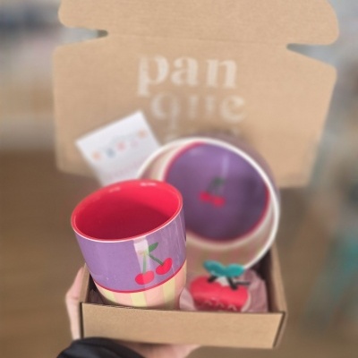 Conjunto cerâmico com copo e prato decorados com cerejas dentro de caixa de cartão