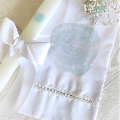 Vela branca com fita e toalha branca com padrão azul e nome Rafael