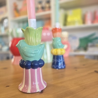 Dois castiçais coloridos de cerâmica com aves e padrões em mesa de madeira