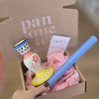 Caixa de cartão com castiçal de cerâmica colorido e vaso azul claro em papel rosa