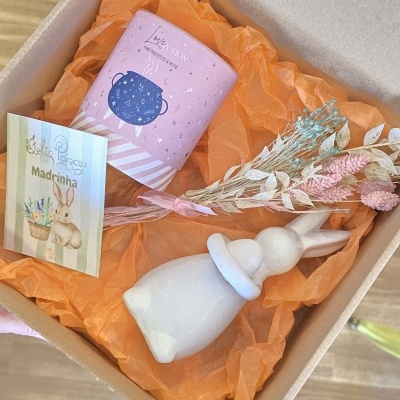 Caixa de presente com vela cor-de-rosa, ramo de flores secas e figura decorativa de coelho branco