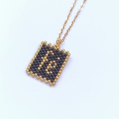 Colar com pendente quadrado em contas pretas e douradas com palavra 'fé'