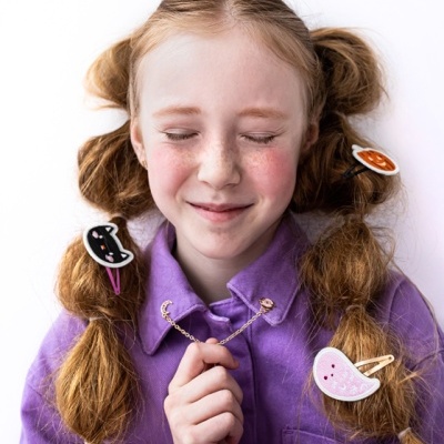 Menina ruiva com acessórios de Halloween no cabelo e camisa roxa