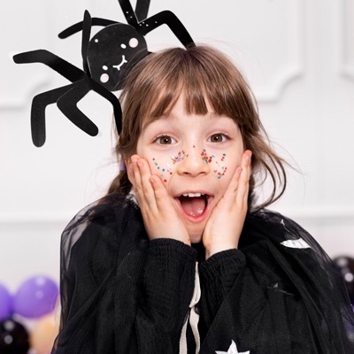 Criança com fantasia preta e adereço de aranha na cabeça