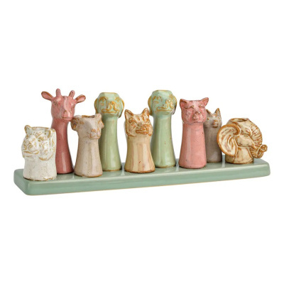 Esculturas em cerâmica de cabeças de animais em tons pastel numa base verde