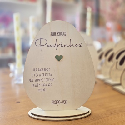 Placa decorativa em madeira clara com texto para padrinhos e coração verde.