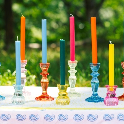 Candelabros de vidro colorido com velas finas várias cores em mesa ao ar livre