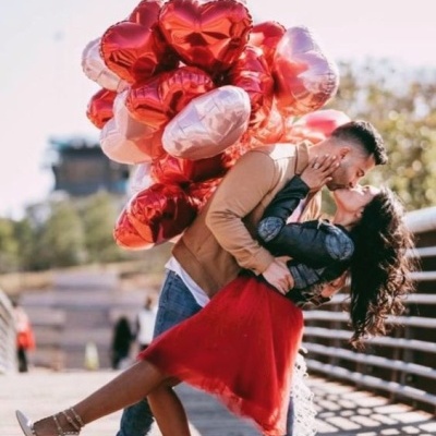Casal apaixonado com balões de coração num passadiço exterior