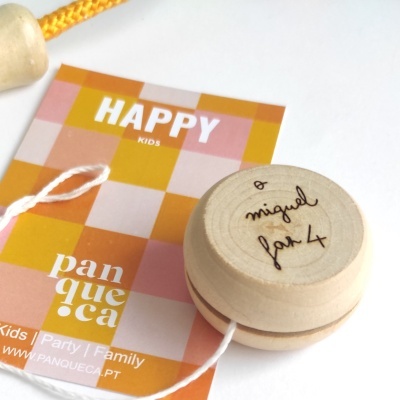 Ioiô de madeira clara com corda branca sobre cartão colorido com texto