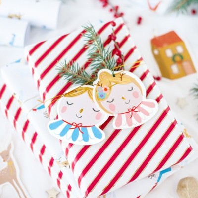 Presente embrulhado com papel listrado vermelho e branco e etiqueta de anjos natalícios