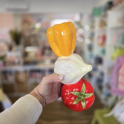 Escultura decorativa em cerâmica com pimento amarelo, alho branco e tomate vermelho brilhante.