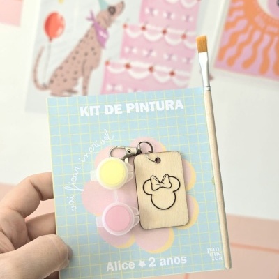 Kit de pintura com tintas, pincel e chaveiro de madeira em embalagem azul com texto.