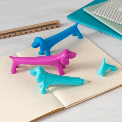 Canetas em forma de cães coloridas sobre caderno quadriculado