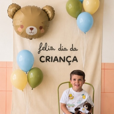 Painel decorativo com texto, balões e criança a segurar urso de peluche