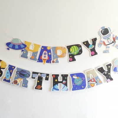 Decoração de festa com letras temáticas espaciais formando HAPPY BIRTHDAY