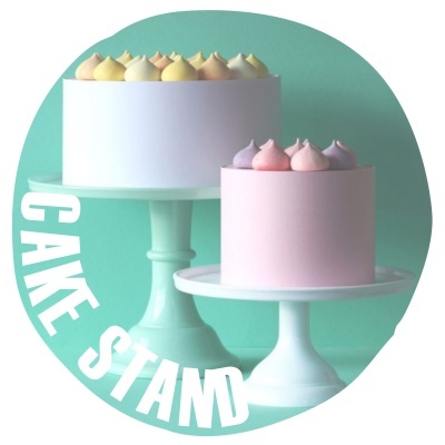 Dois bolos coloridos em suportes brancos com fundo verde e texto 'CAKE STAND'.