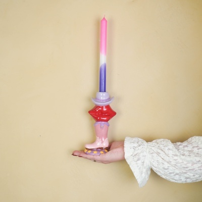 Castical colorido em cerâmica com vela tricolor segurado por mão com manga rendada branca