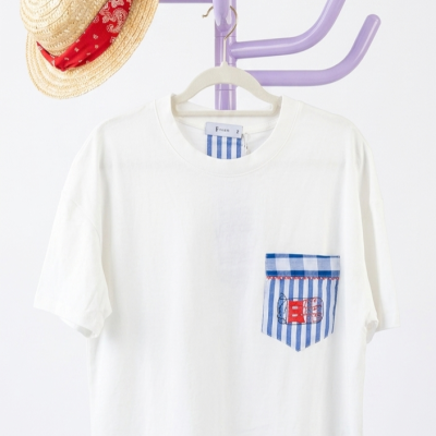 T-shirt branca com bolso às riscas azuis e um chapéu de palha com lenço vermelho